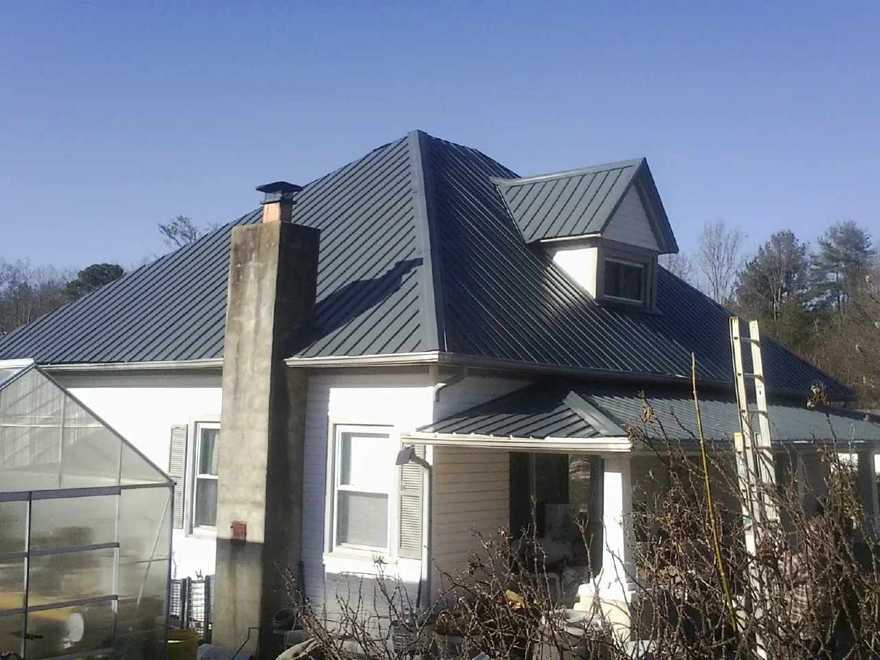 Dark blue standing seam metal roof on a white farmhouse with dormer — Slate & Tile Roof Repair by Roofing Brothers in Petrolia