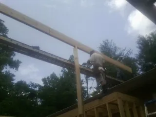 Carpenter setting a ridge beam over a new addition frame — Ice Dam Removal by Roofing Brothers in Petrolia