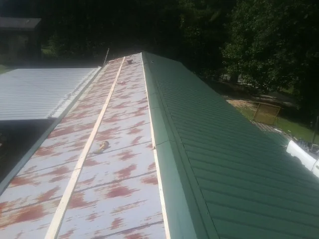 Old rusted panels beside newly installed green metal roofing — Wind Damage Roof Repair by Roofing Brothers in Petrolia