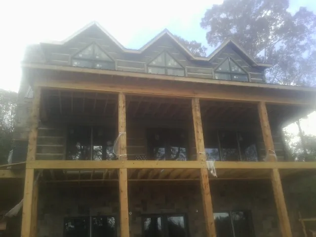 Dormers and porch framing on a large log home under construction — Roof Coating work by our crew in Petrolia