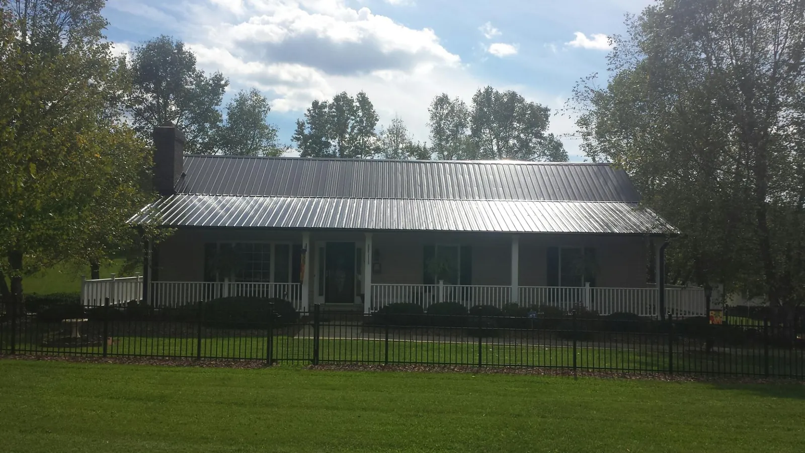 Gray metal roof on a brick ranch with a full width front porch — Gutter Guard Installation work by our crew in Petrolia