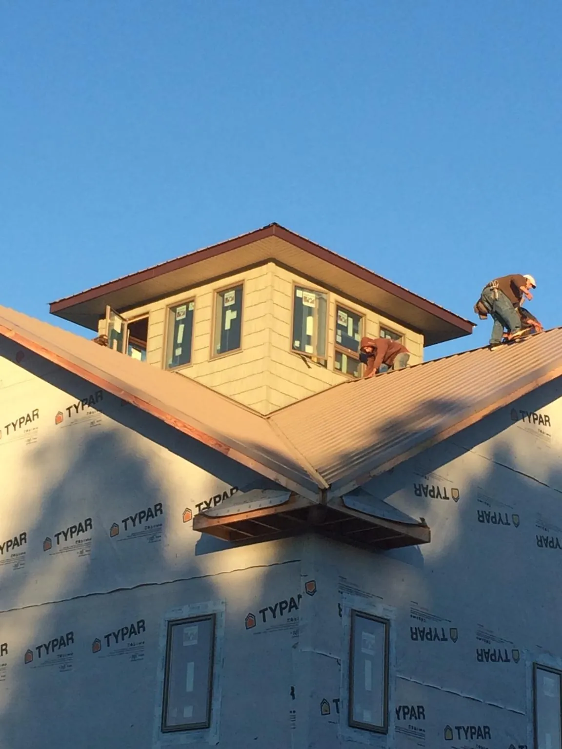 Roofers working around a rooftop cupola on a new metal roof at sunset — Roof Waterproofing in Petrolia by Roofing Brothers